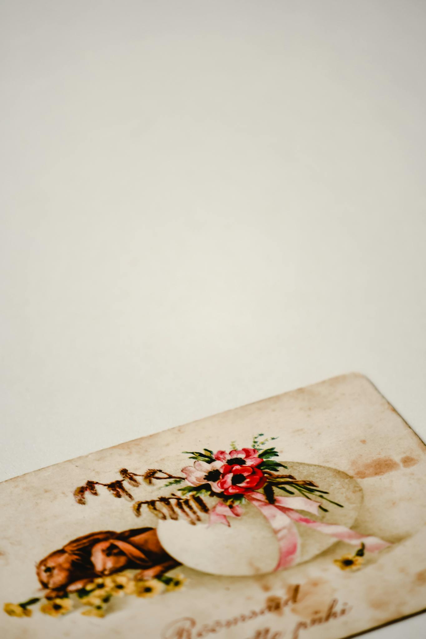 An antique greeting card with floral design on a white table.